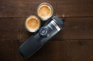 Bærbar espressomaskine med to kopper espresso på træbord, fra bærbare kaffemaskiner og barista-udstyr